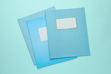 Colorful copybooks on light blue background, flat lay. School stationery
