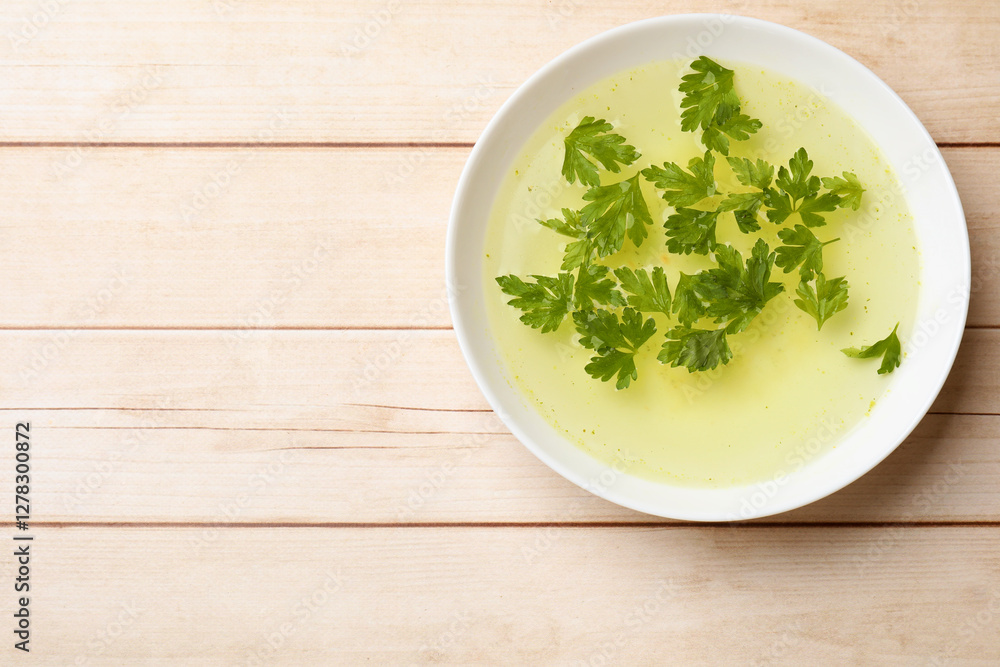 Sticker Tasty chicken bouillon with parsley in bowl on wooden table, top view. Space for text