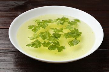 Tasty chicken bouillon in bowl on wooden table, closeup