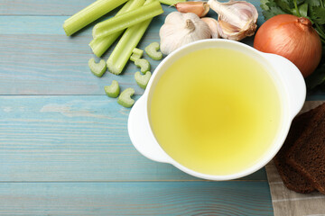 Tasty chicken bouillon served on light blue wooden table, flat lay. Space for text
