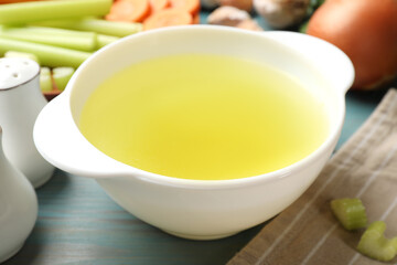 Tasty chicken bouillon served on light blue wooden table, closeup