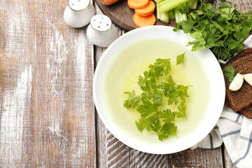 Tasty chicken bouillon served on wooden table, flat lay. Space for text