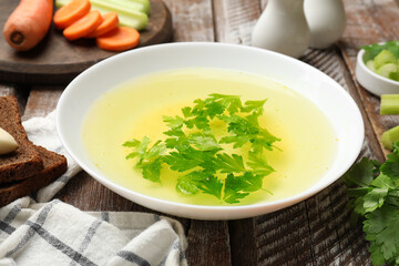 Tasty chicken bouillon served on wooden table, closeup