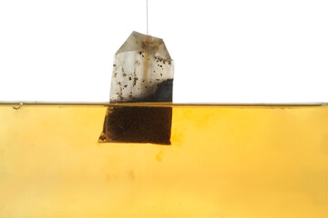 Putting tea bag into glass cup on white background, closeup