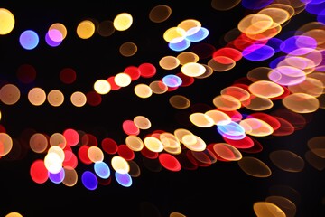 Blurred view of colorful lights on black background, bokeh effect