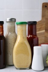 Tasty sauces in glass bottles on white table, closeup