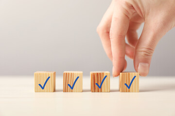 Woman taking cube with check mark at table, closeup