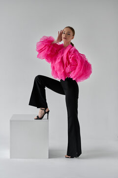 beautiful woman in pink blouse and black pants on white background