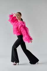 beautiful woman in pink blouse and black pants on white background