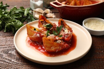 Delicious conchiglie pasta with ricotta cheese, tomato sauce and parsley on wooden table, closeup