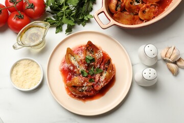 Delicious conchiglie pasta with ricotta cheese, tomato sauce and parsley on white table, flat lay