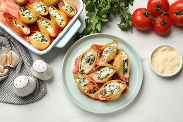 Delicious shell pasta stuffed with ricotta and spinach served on white table, flat lay