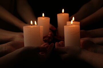 Women with burning candles on dark background, closeup