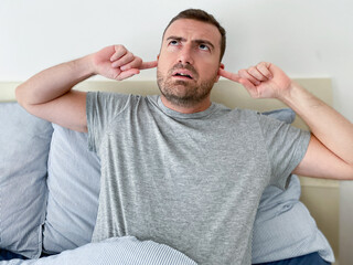Portrait of angry man in bed annoyed by noise