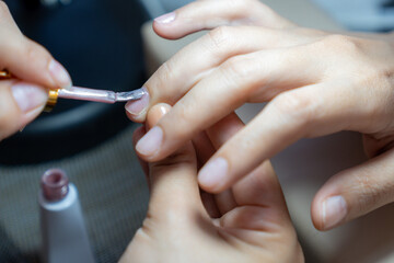 The manicure coats nails with gel polish in the beauty salon.