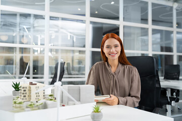 Young female caucasian architect working on a building model in the office