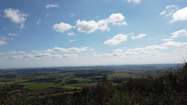 Panoramic view of Sion Hill in Vaud&eacute;mont, showcasing expansive fields and a serene sky.