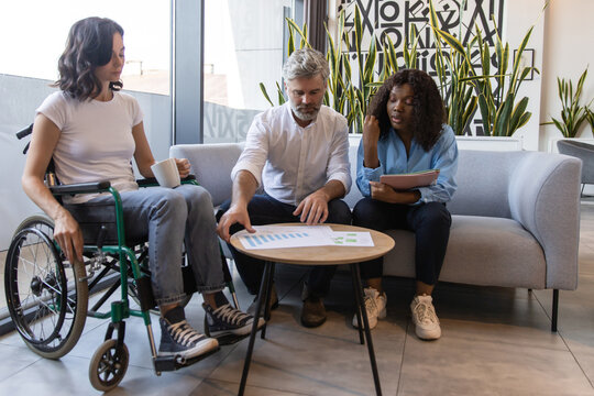 Diverse team in workplace including woman in wheelchair collaborating on business strategy