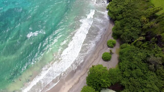 Hamoa Beach Hana Maui Hawaii &ndash; Breathtaking tilt-up aerial cinematic video revealing crystal-clear blue waters, waves, lush tropical greenery, and lava rock formations along Maui&rsquo;s stunning coastline.