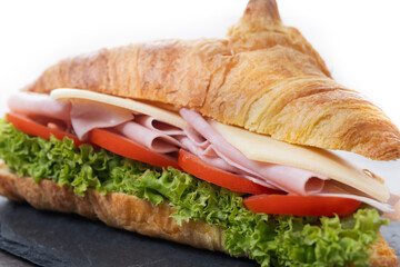 Croissant with ham, cheese and vegetables on wooden table