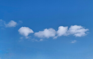 clouds resembling a large caterpillar
small white clouds lined up one after another in a curved line on the blue sky