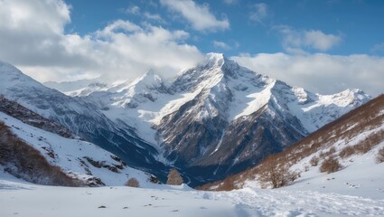 Majestic snow-covered mountain range under a blue sky showcasing the serene beauty of winter wilderness and rocky peaks.