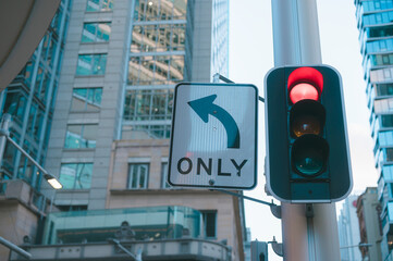 Red traffic light and right turn only arrow sign in city with blurred city background