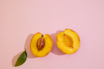 Top view of halved peach on a pink background with copy space. Orange fruit with velvety skin and juicy, sweet and aromatic pulp