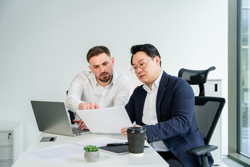 Confident professionals reviewing documents during a meeting in a modern office, creating collaborative strategies and ideas. The individuals display focus, teamwork, wearing formal attire.