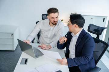 Professional businessmen in sleek office attire discussing a business strategy in a modern office...