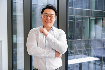 Professional Korean businessman in a bright office setting, wearing a formal white shirt, exuding...