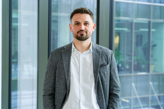 Professional and confident businessman standing in a modern office environment wearing a stylish suit, showcasing a corporate and focused demeanor.