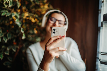 Young caucasian woman listen to music and sing by the window	
