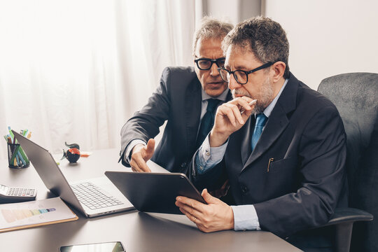 Senior business executives reviewing financial data on tablet in office
