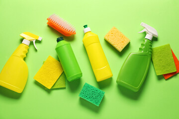 Cleaning products and tools on green background, flat lay