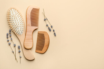 Wooden hair brush, combs and lavender flowers on beige background, flat lay. Space for text