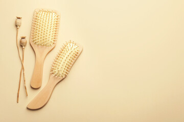 Wooden hair brushes and poppy heads on beige background, top view. Space for text