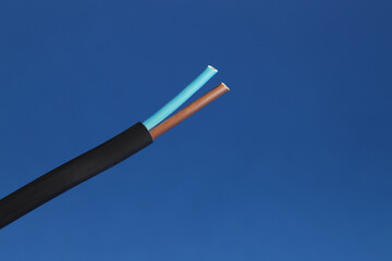 Black stripped electrical wire on blue background, closeup. Space for text