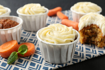 Delicious carrot muffins with fresh vegetables on black table, closeup