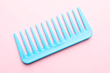 One light blue plastic comb on pink background, top view