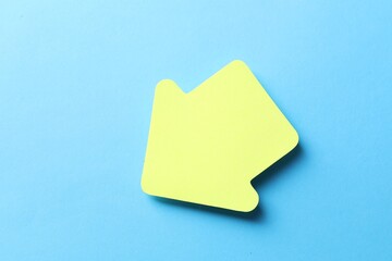 One yellow paper arrow on light blue background, top view
