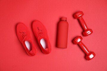 Dumbbells, water bottle and sneakers on red background, flat lay. Sports equipment