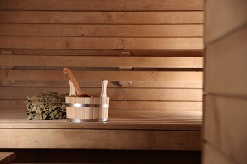 Bucket, ladle and whisk on wooden bench in sauna. Space for text