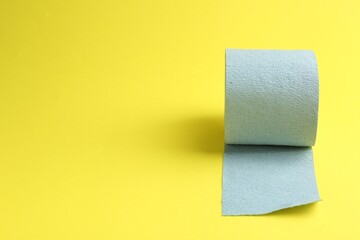 Light blue toilet paper roll on yellow background, space for text