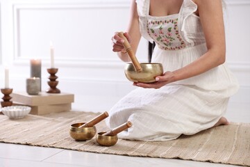 Woman with singing bowls on floor indoors, closeup