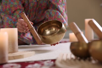 Woman with singing bowls and burning candles indoors, closeup