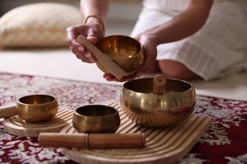 Woman with singing bowls on floor indoors, closeup