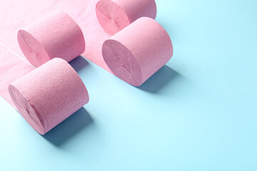 Pink toilet paper rolls on light blue background, space for text