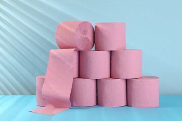 Stack of pink toilet paper rolls on light blue background