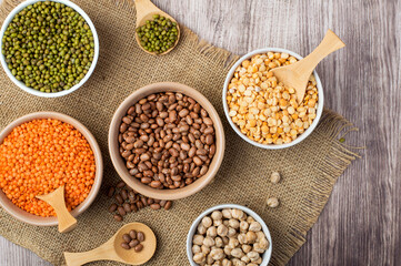 Assortment of legume products in bowls on cloth, burlap. Top view, horizontal. Healthy nutrition, vegetarianism.